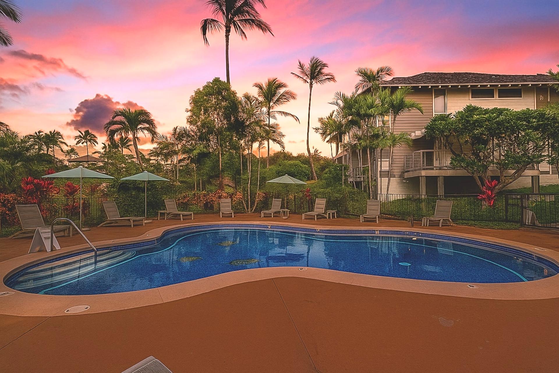 As the sun sets over a tropical paradise, soft hues of pink and orange reflect off the tranquil waters of a resort pool surrounded by swaying palm trees and lush greenery. 
