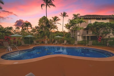 As the sun sets over a tropical paradise, soft hues of pink and orange reflect off the tranquil waters of a resort pool surrounded by swaying palm trees and lush greenery.