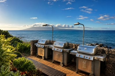 Oceanfront BBQ grills at Mahina Surf — three propane grills on the seawall patio, ready for a sunset cookout