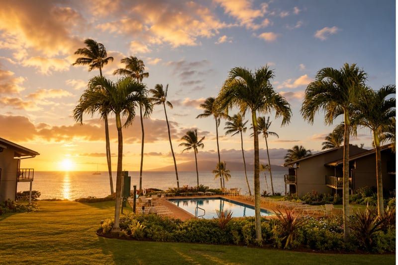Sunset over the pool deck at Mahina Surf — golden-hour views across the channel with a sailboat drifting past