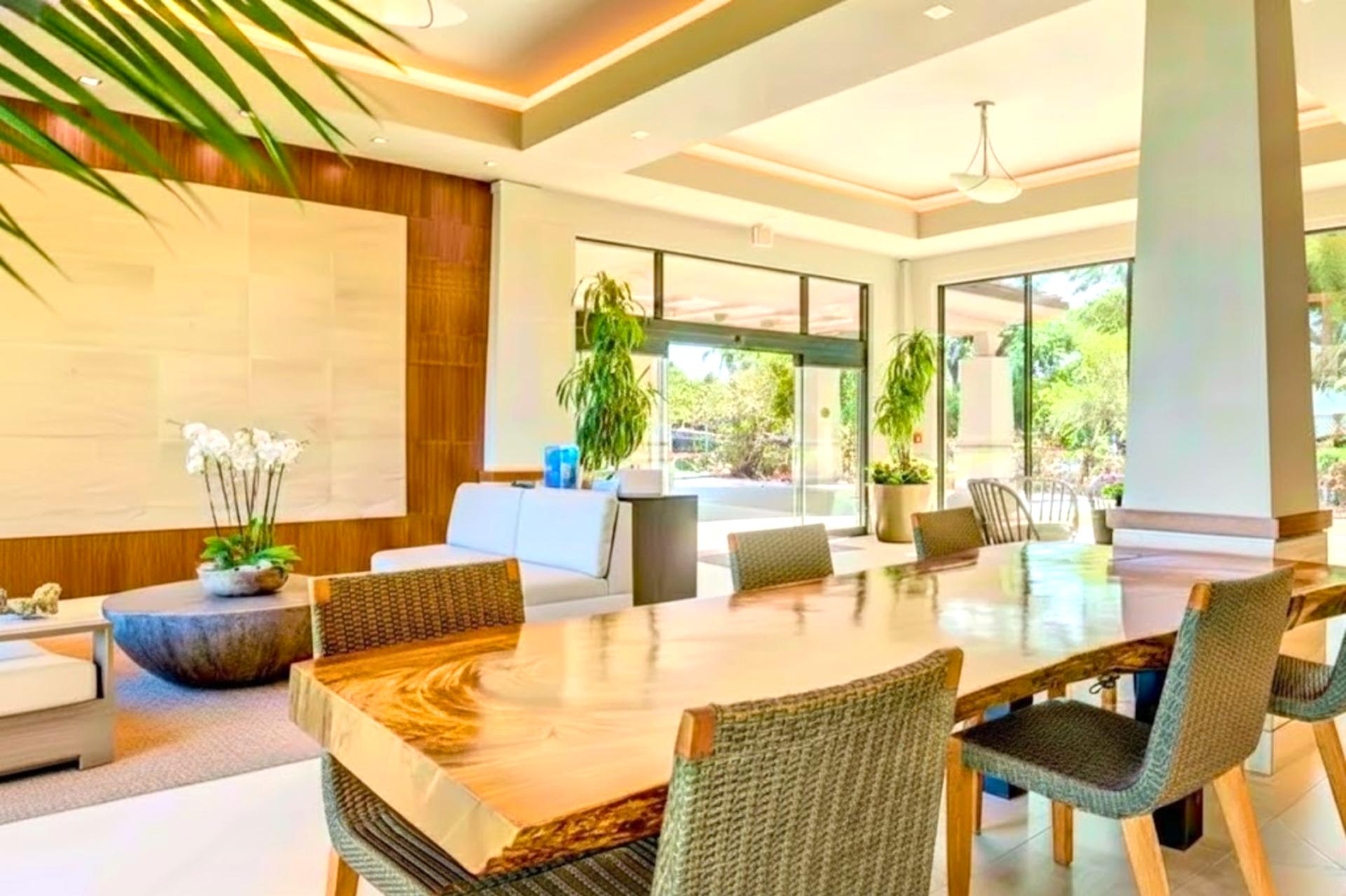Spacious open-air lobby with modern tropical design, natural light, elegant seating, and lush resort garden surroundings