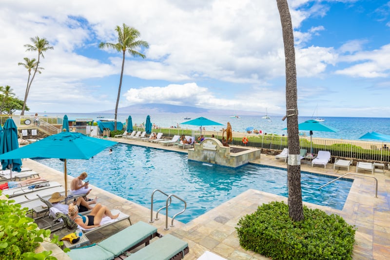 Oceanfront pool with panoramic beach views, private loungers, poolside umbrellas, tropical gardens & island relaxation