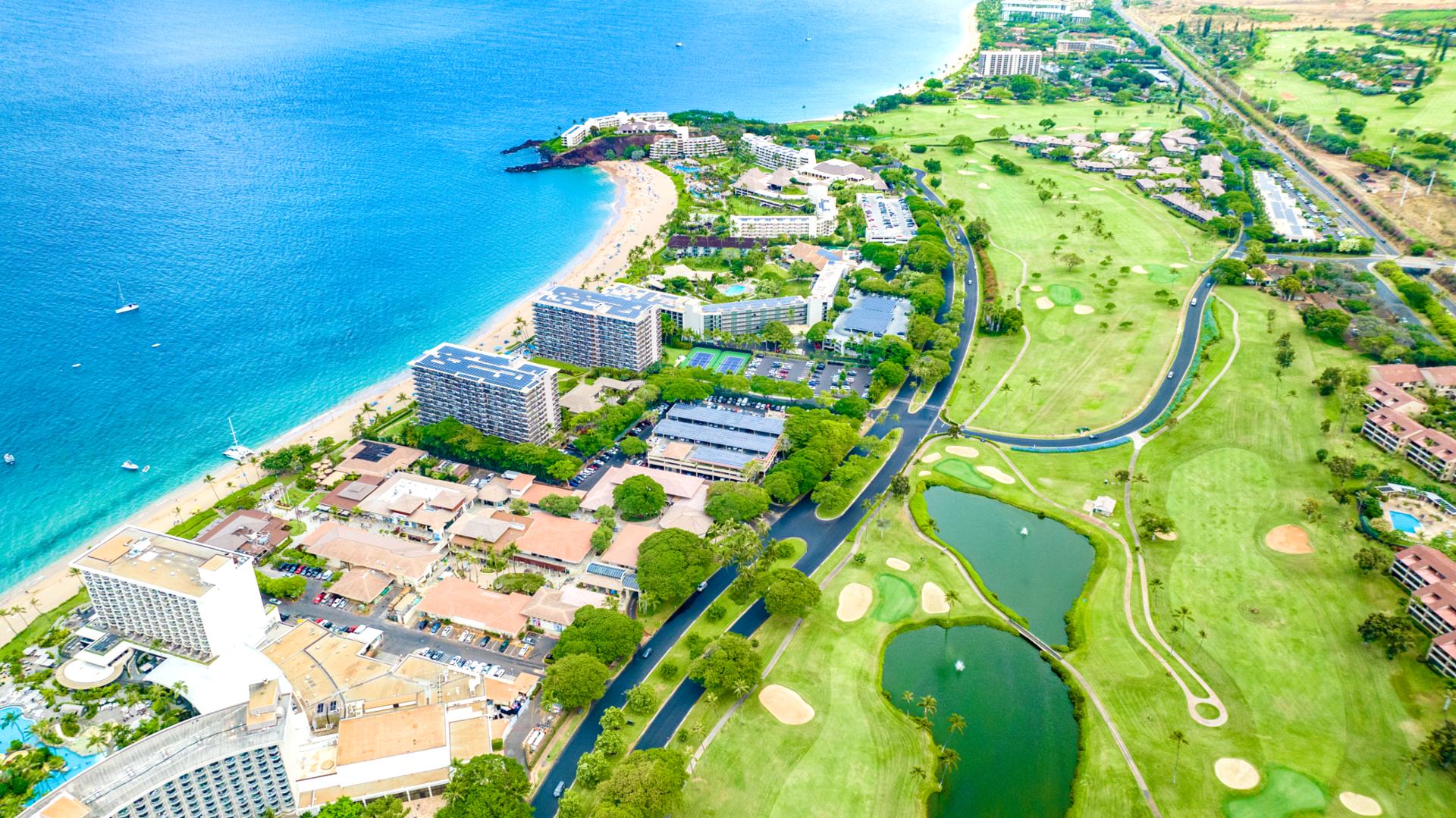 Drone view of beachfront Whaler resort with infinity pools, luxury condos, beach umbrellas, and crystal-clear shoreline