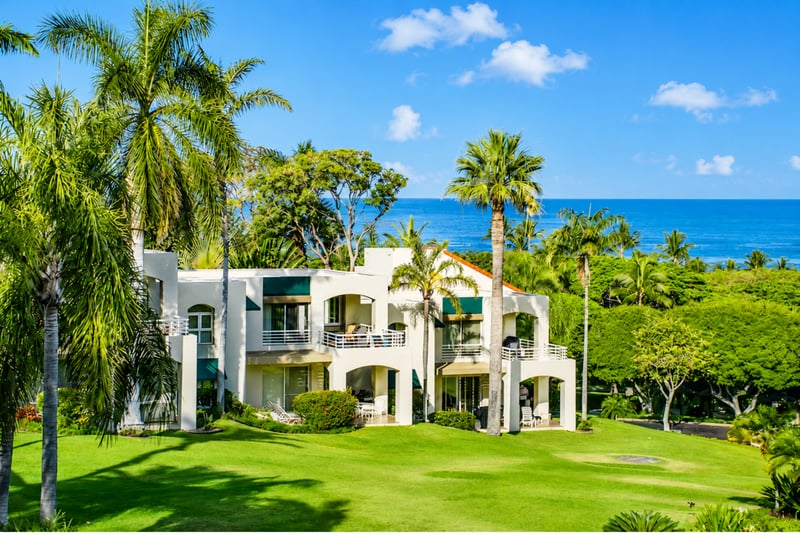 Spacious island-style architecture framed by manicured grounds and vibrant tropical greenery.
