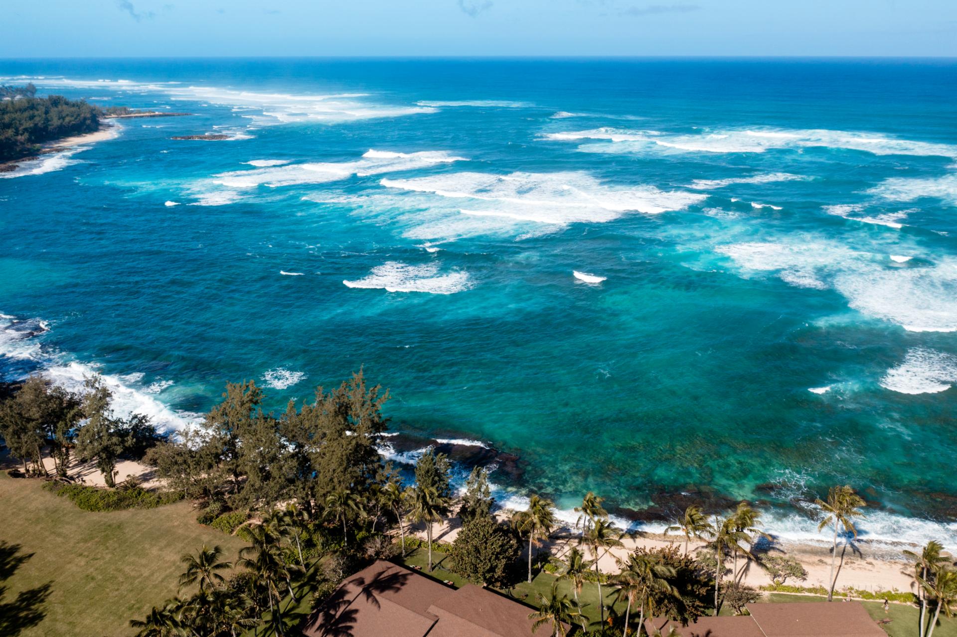 Sweeping aerial of Oahu’s North Shore, where the turquoise waters and reef-lined coast meet the peaceful edge of Kuilima Estates.
