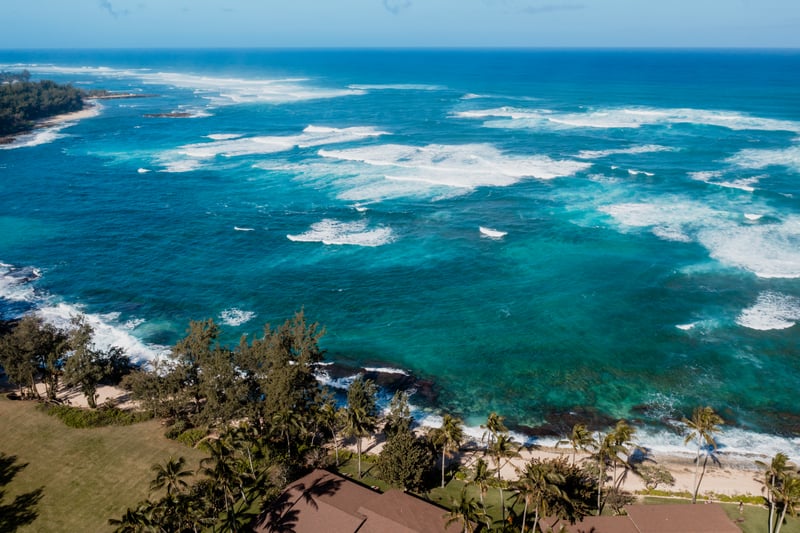 Sweeping aerial of Oahu’s North Shore, where the turquoise waters and reef-lined coast meet the peaceful edge of Kuilima Estates.