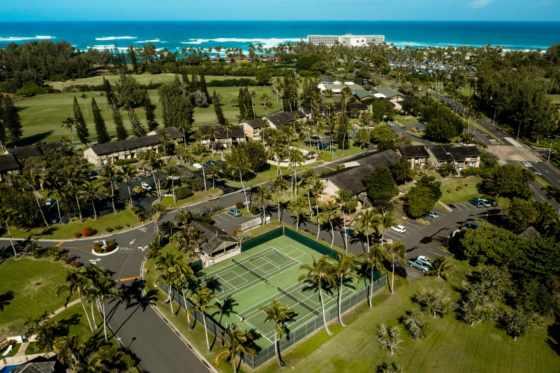 Tennis courts at Kuilima Estates are surrounded by palm trees and ocean breezes, offering a scenic spot to play with beach access just beyond.