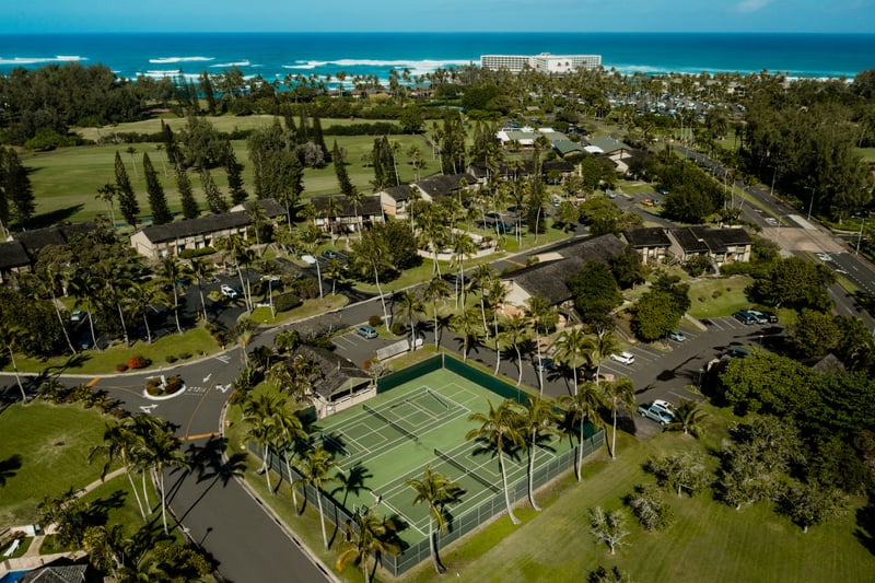 Tennis courts at Kuilima Estates are surrounded by palm trees and ocean breezes, offering a scenic spot to play with beach access just beyond.