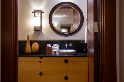 This guest bathroom blends warm wood tones, elegant lighting, and sleek finishes to offer a spa-like experience