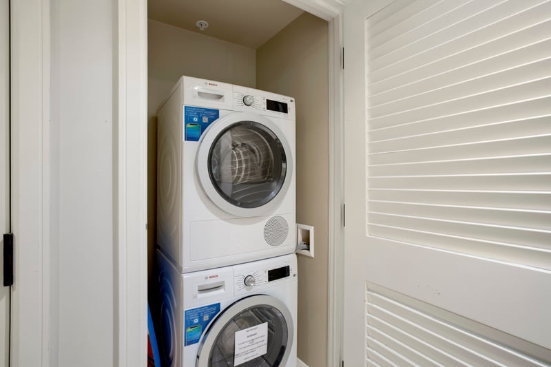 Compact laundry closet with modern Bosch stacked washer and dryer. HKK-220