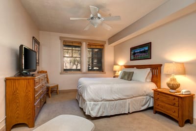 This sunlit guest suite offers a Queen bed, natural wood furnishings, and a peaceful setting for restful nights. TPC-102C