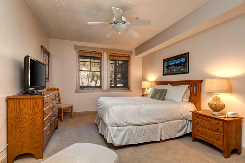 This sunlit guest suite offers a Queen bed, natural wood furnishings, and a peaceful setting for restful nights.