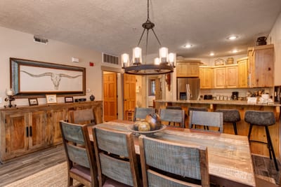 This spacious dining area features rustic charm, a central chandelier, and open sightlines to the kitchen and great room. TPC-102C