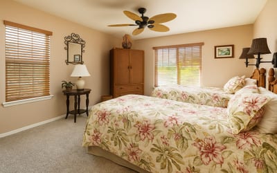 Charming twin bedroom with floral linens, natural light, and tropical elegance throughout