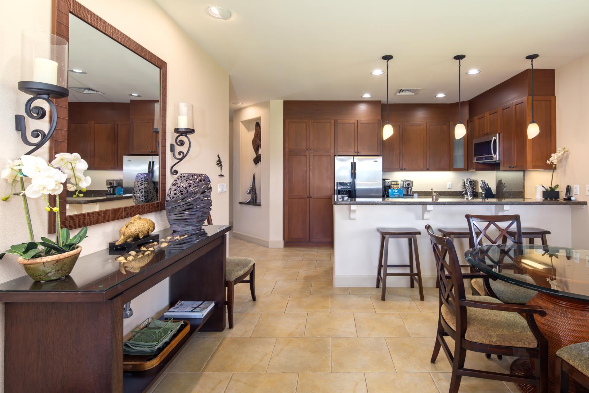 Sleek kitchen with rich wood cabinetry, pendant lighting, and stainless steel appliances