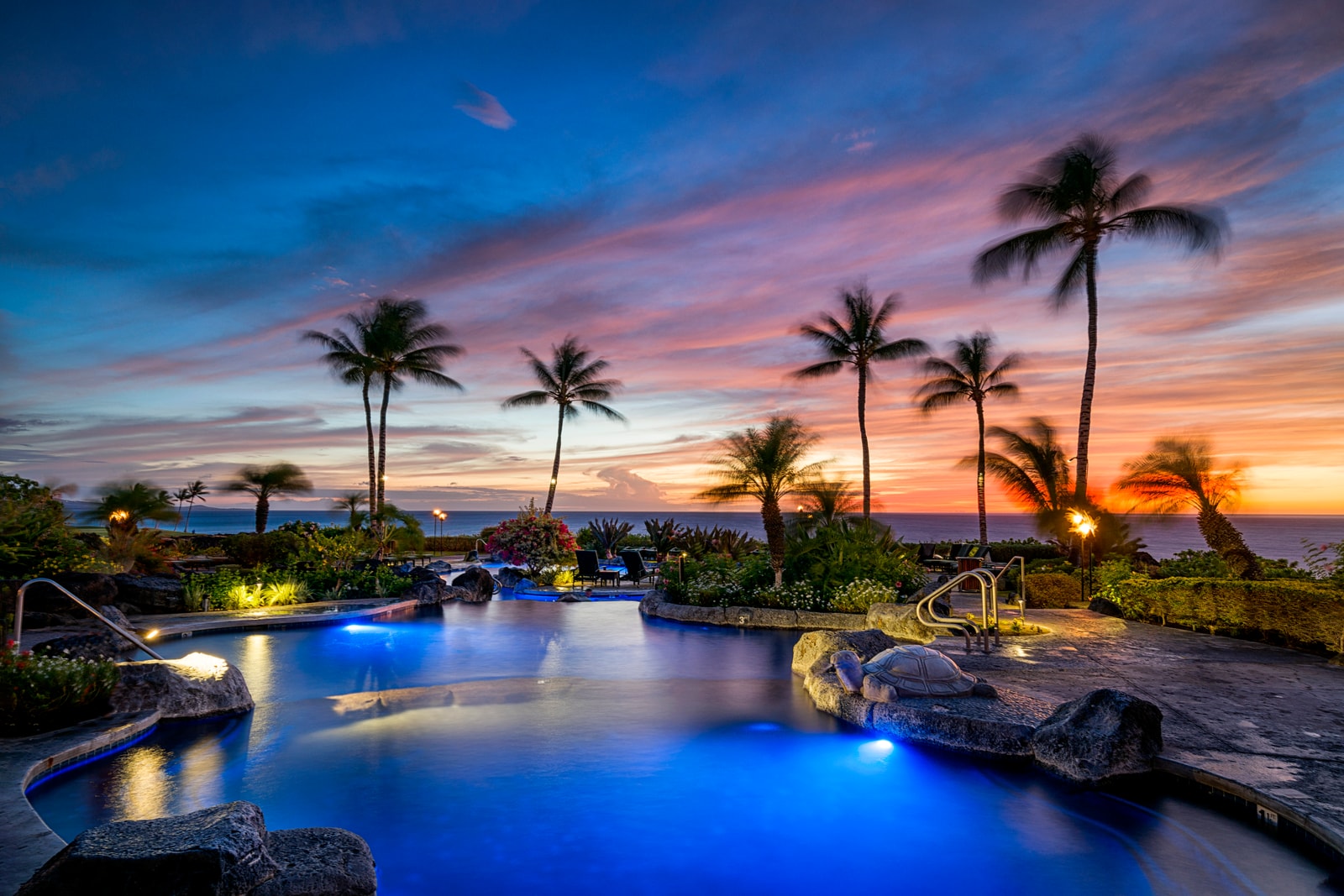 Evening dips feel magical in the resort’s lagoon-style pool, glowing under a tropical sunset sky.