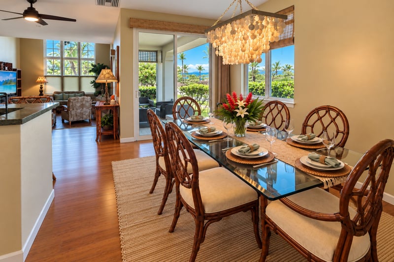 Glass top dining table set with six chairs beside a sliding door to the lanai, with palm views through the windows.