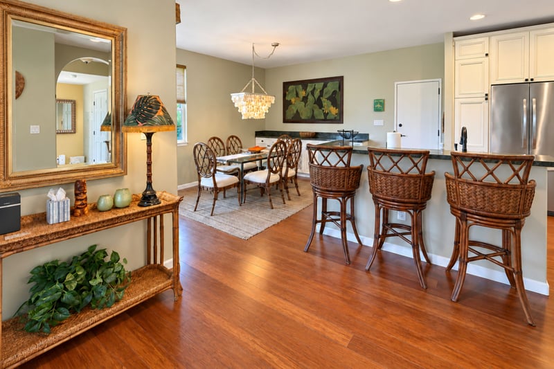 An entry console and mirror lead into the open dining area and kitchen, with three swivel bar stools at the breakfast counter.
