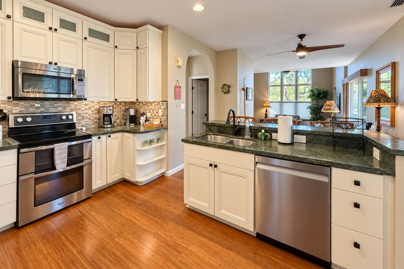 Open kitchen with a double oven range, dishwasher, and a peninsula counter that looks out to the living area.