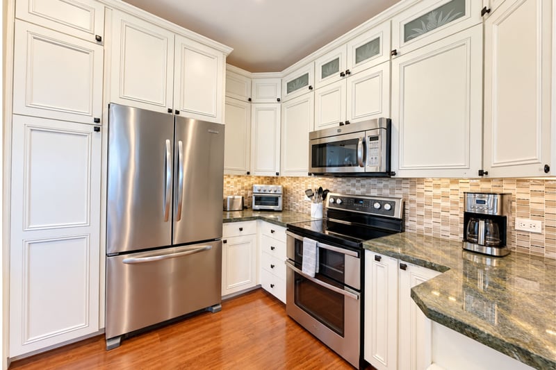 Kitchen with a stainless steel French door refrigerator, over-range microwave, cream cabinetry, and a mosaic tile backsplash.