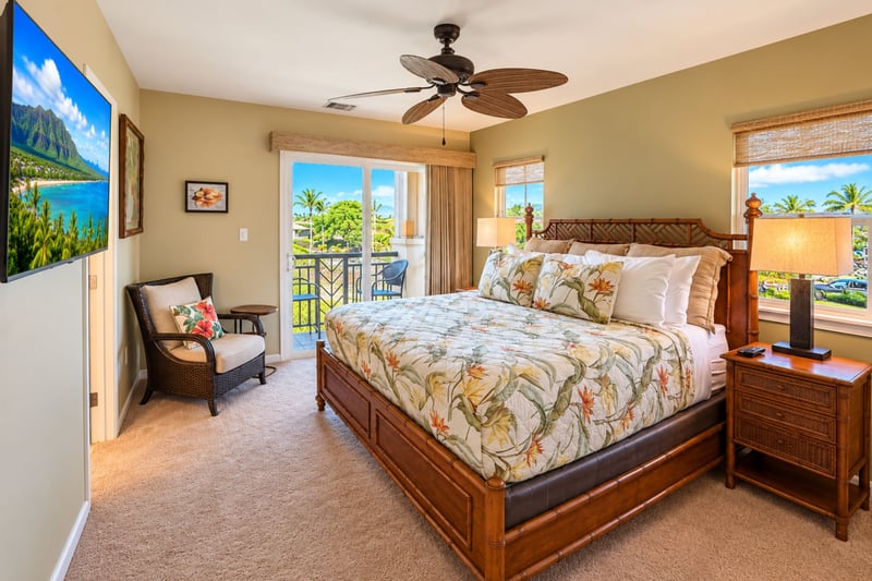 Primary bedroom with a king bed, ceiling fan, and a sliding door that opens to a balcony.