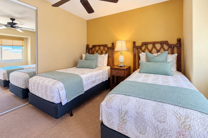Bedroom with two twin beds, rattan headboards, and a mirrored closet, a good fit for kids or friends.