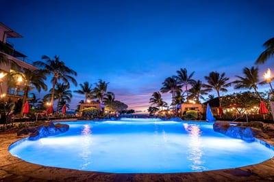 Tropical twilight glow over a serene, torch-lit resort pool. HKH-222