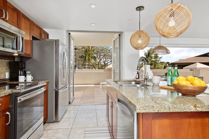 Spacious island kitchen opens to sun-drenched lanai and palm views