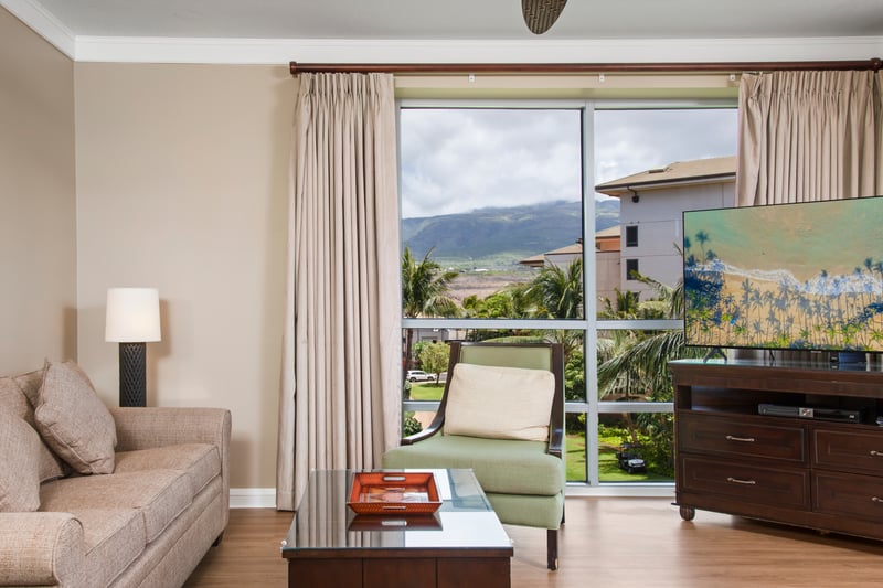 Bask in natural light and mountain views from this sleek, peaceful living room with soft tones and modern charm
