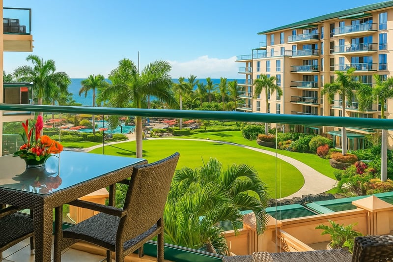 Scenic lanai dining with lush resort landscaping, mountain-lined horizon, and distant ocean sparkle. HKH-423