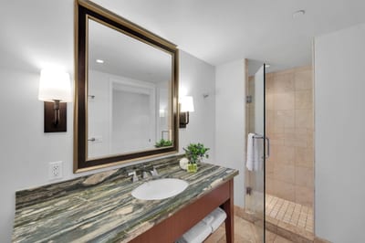 Ensuite bath with glass shower and elegant granite vanity.
