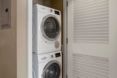 In-unit Bosch washer and dryer tucked behind sleek louvered doors.