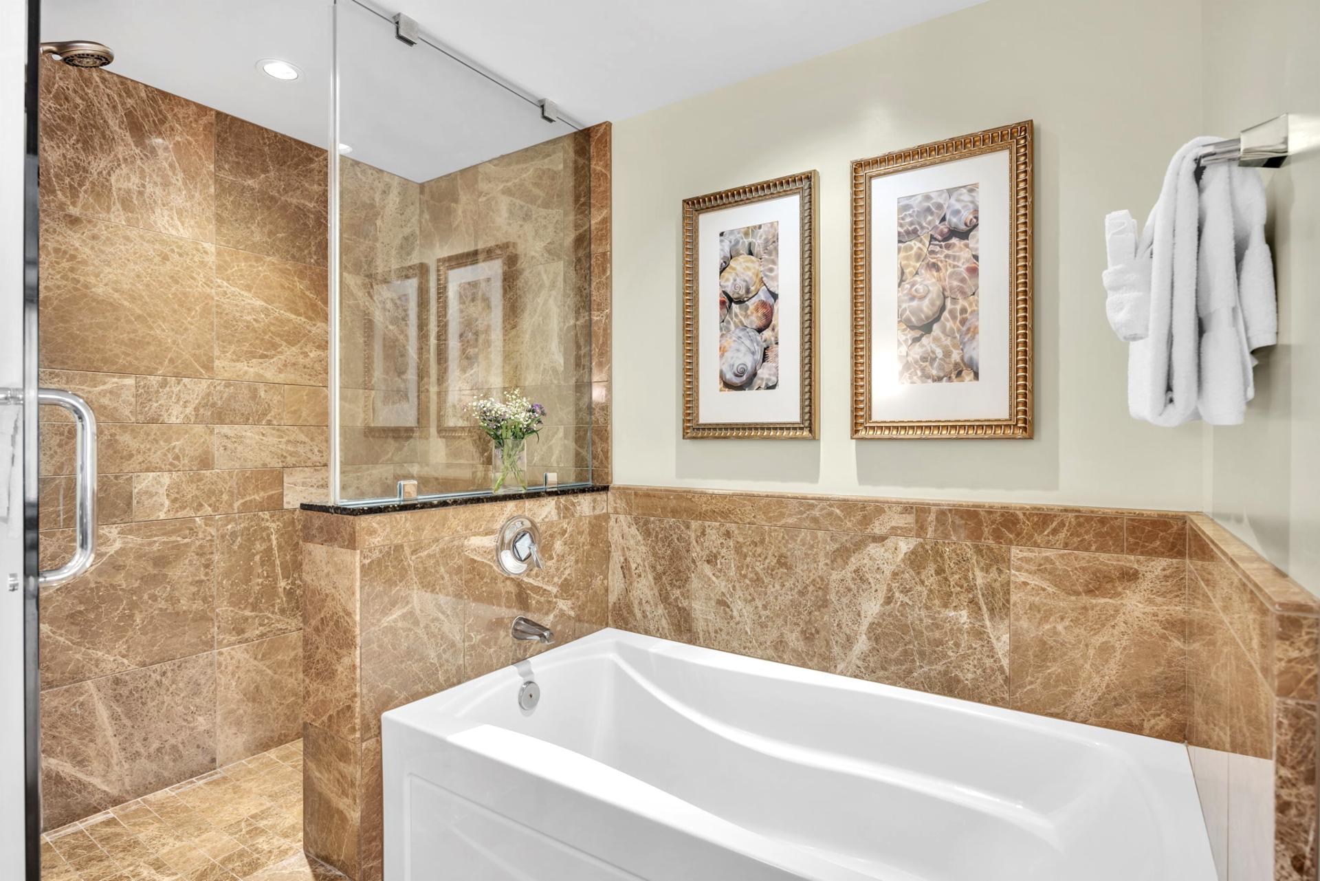 The ensuite guest bathroom features a soaking tub and an elegant walk in shower