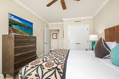 Bright coastal bedroom with TV, tropical accents, and stylish decor.
