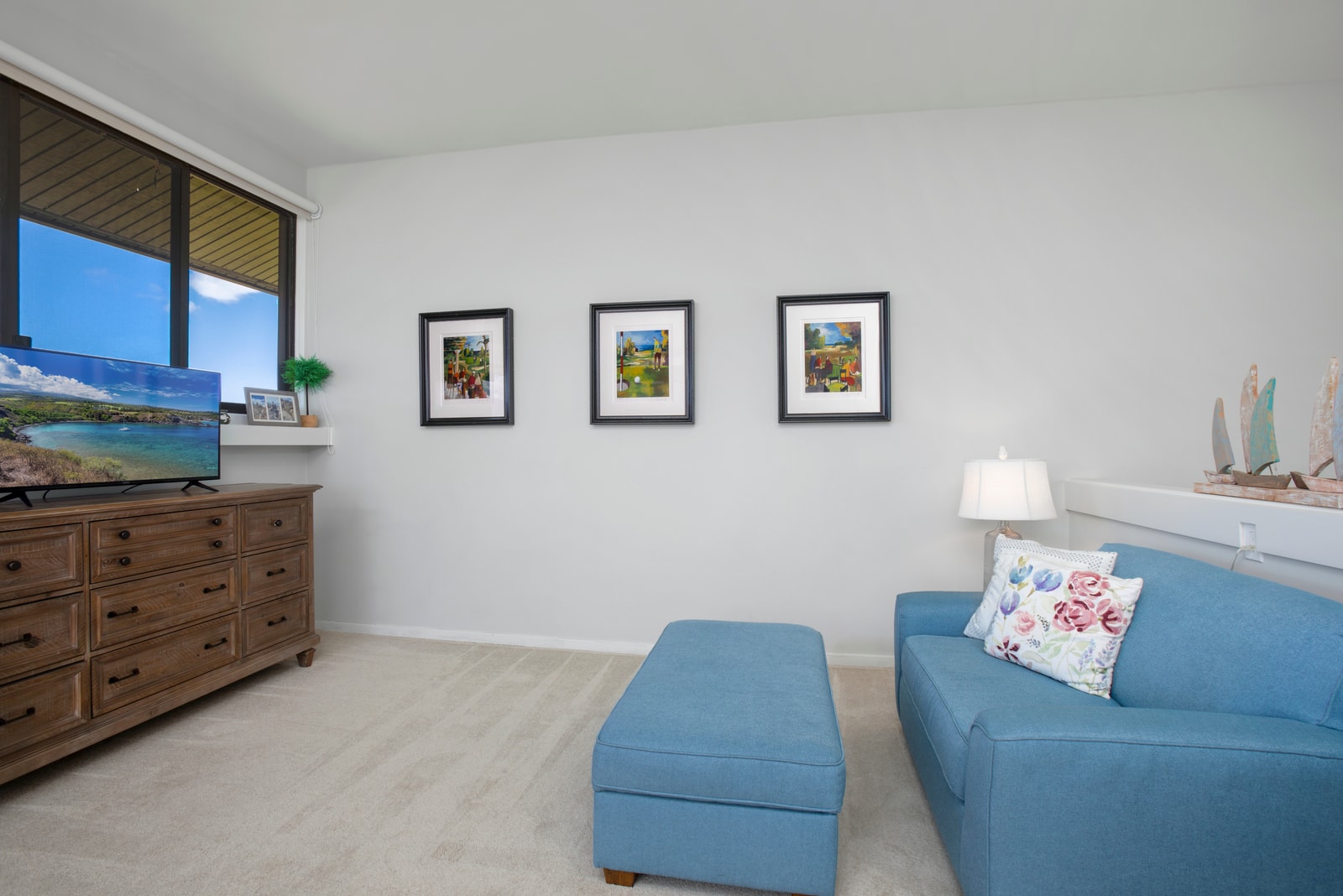 Bright coastal lounge with blue accents, scenic art, and TV view.