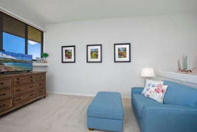 Bright coastal lounge with blue accents, scenic art, and TV view.