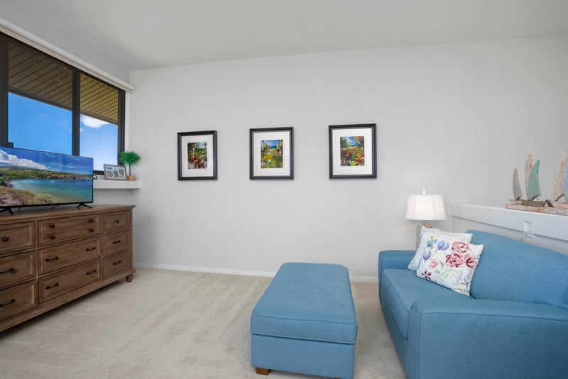 Bright coastal lounge with blue accents, scenic art, and TV view.