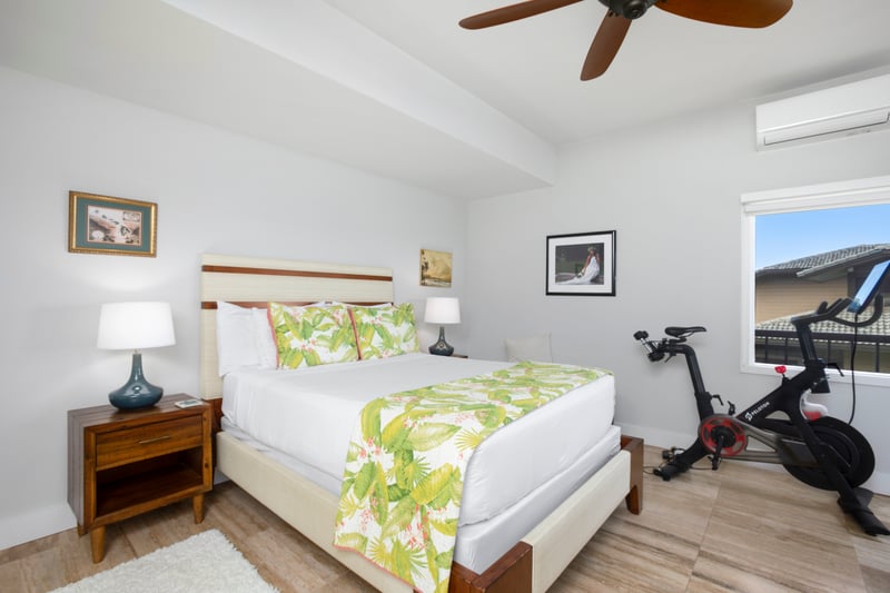 Luxury bedroom oasis with tropical decor and in-room Peloton bike.