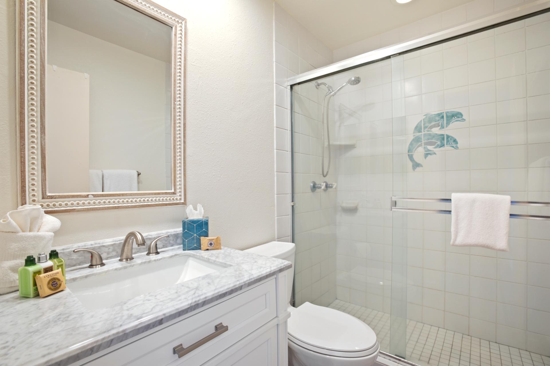 Polished chrome fixtures and a marble-topped vanity blend timeless elegance with breezy comfort in this coastal retreat   