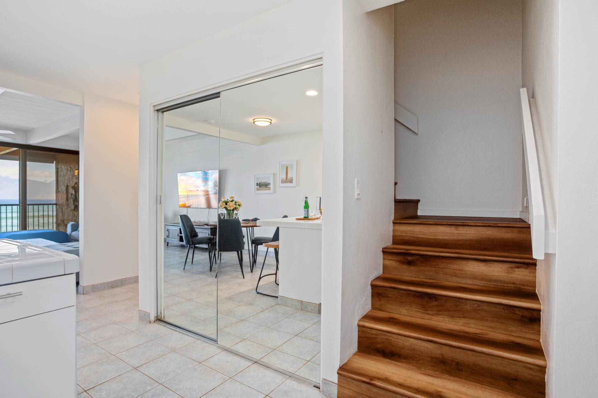 Tucked just beyond the kitchen, a warm wood staircase rises invitingly—promising cozy comforts and ocean-kissed dreams above   
