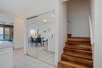 Tucked just beyond the kitchen, a warm wood staircase rises invitingly—promising cozy comforts and ocean-kissed dreams above