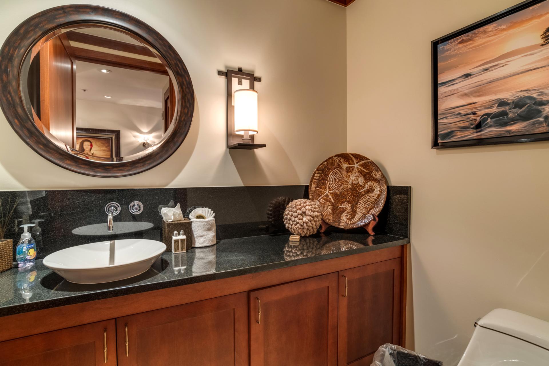 The half bath is well lit and comfortable, featuring a granite countertop and tasteful decor