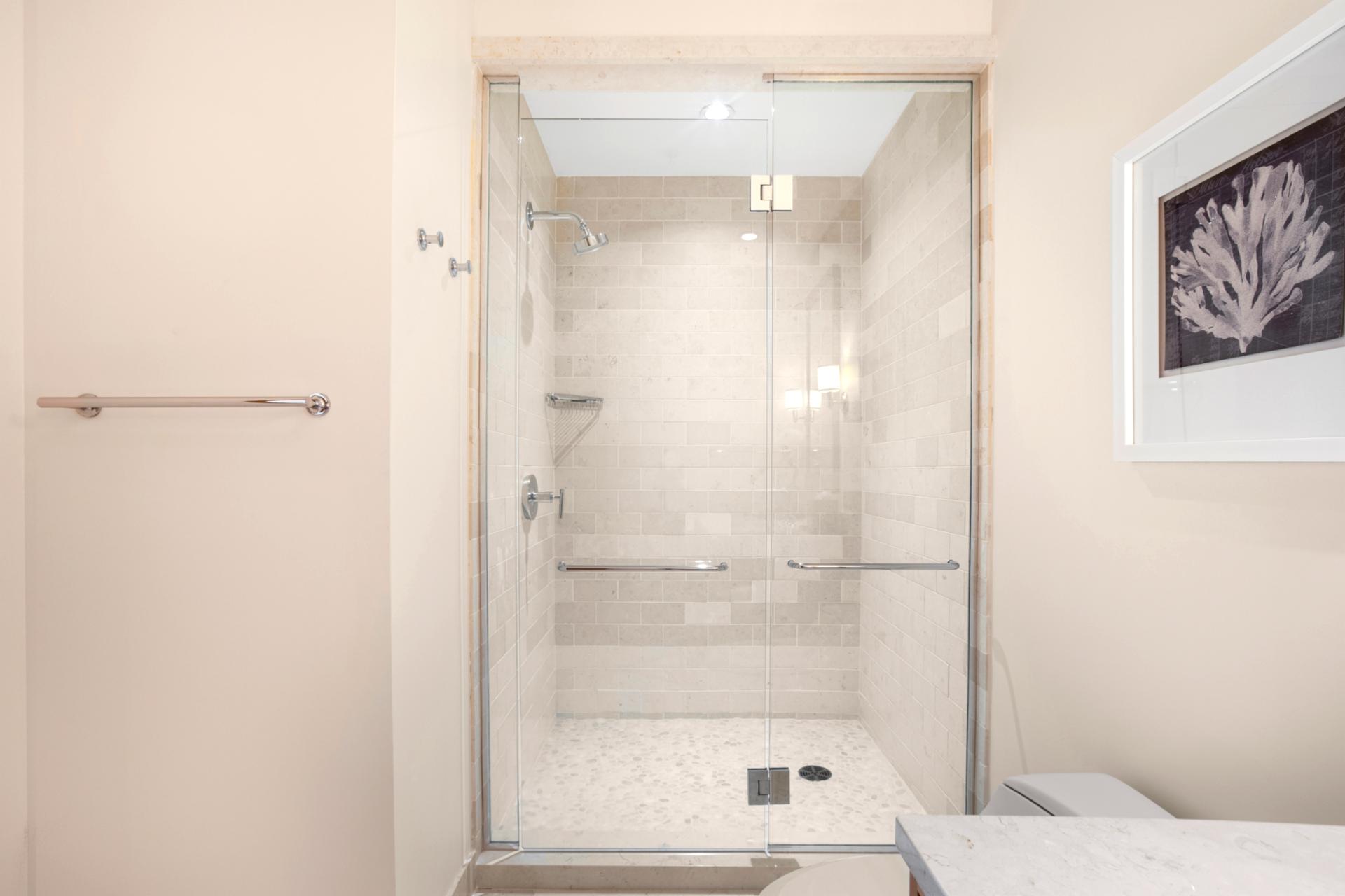 This walk-in shower glows like a pearl, where rainfall gently falls and tile floors feel like cloud-soft seashells   