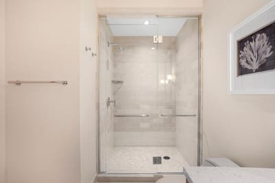 This walk-in shower glows like a pearl, where rainfall gently falls and tile floors feel like cloud-soft seashells