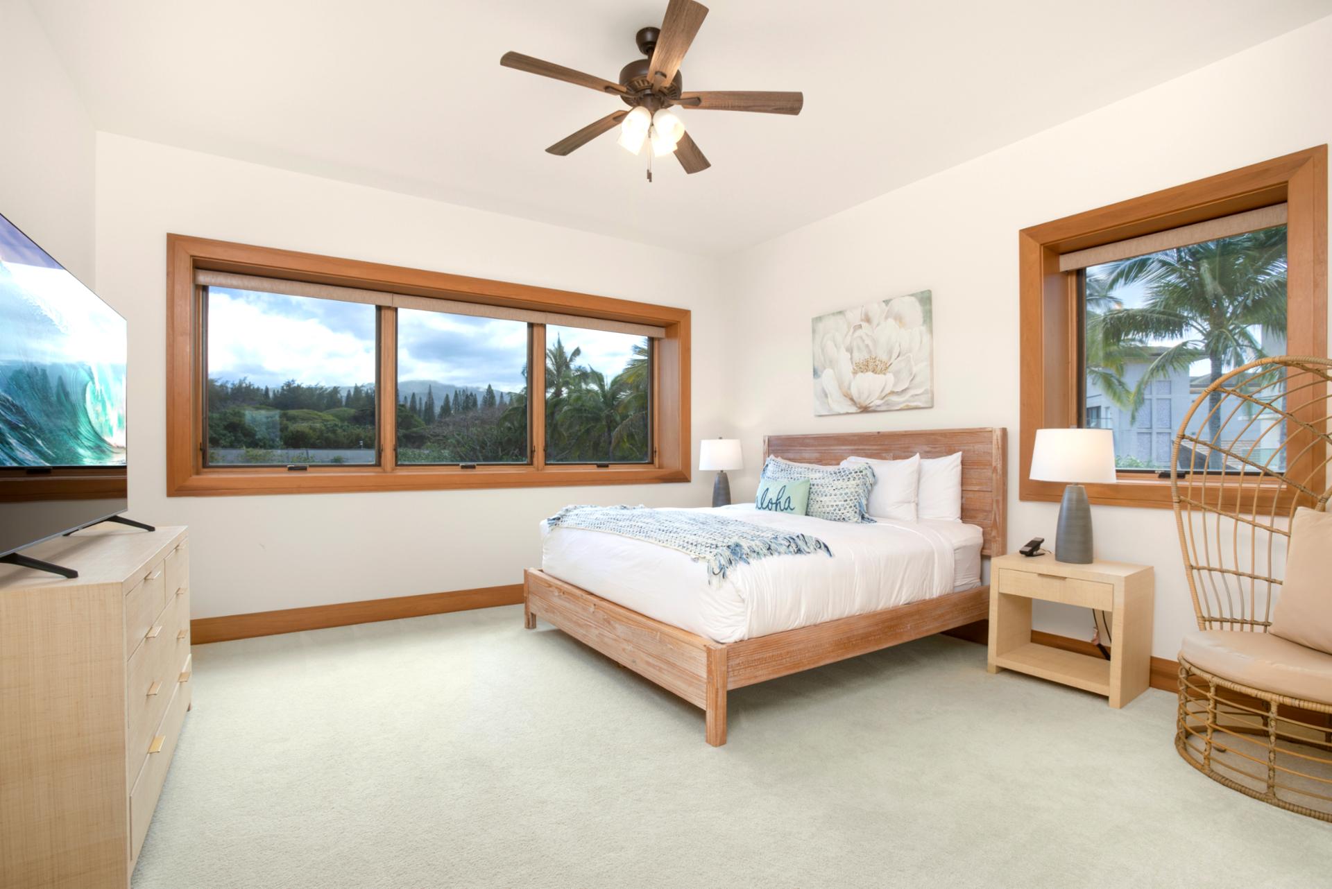 A queen-size bed framed in soft wood anchors this airy guest retreat, surrounded by serene windows with garden views   