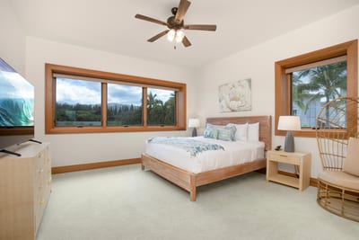 A queen-size bed framed in soft wood anchors this airy guest retreat, surrounded by serene windows with garden views MON-6301