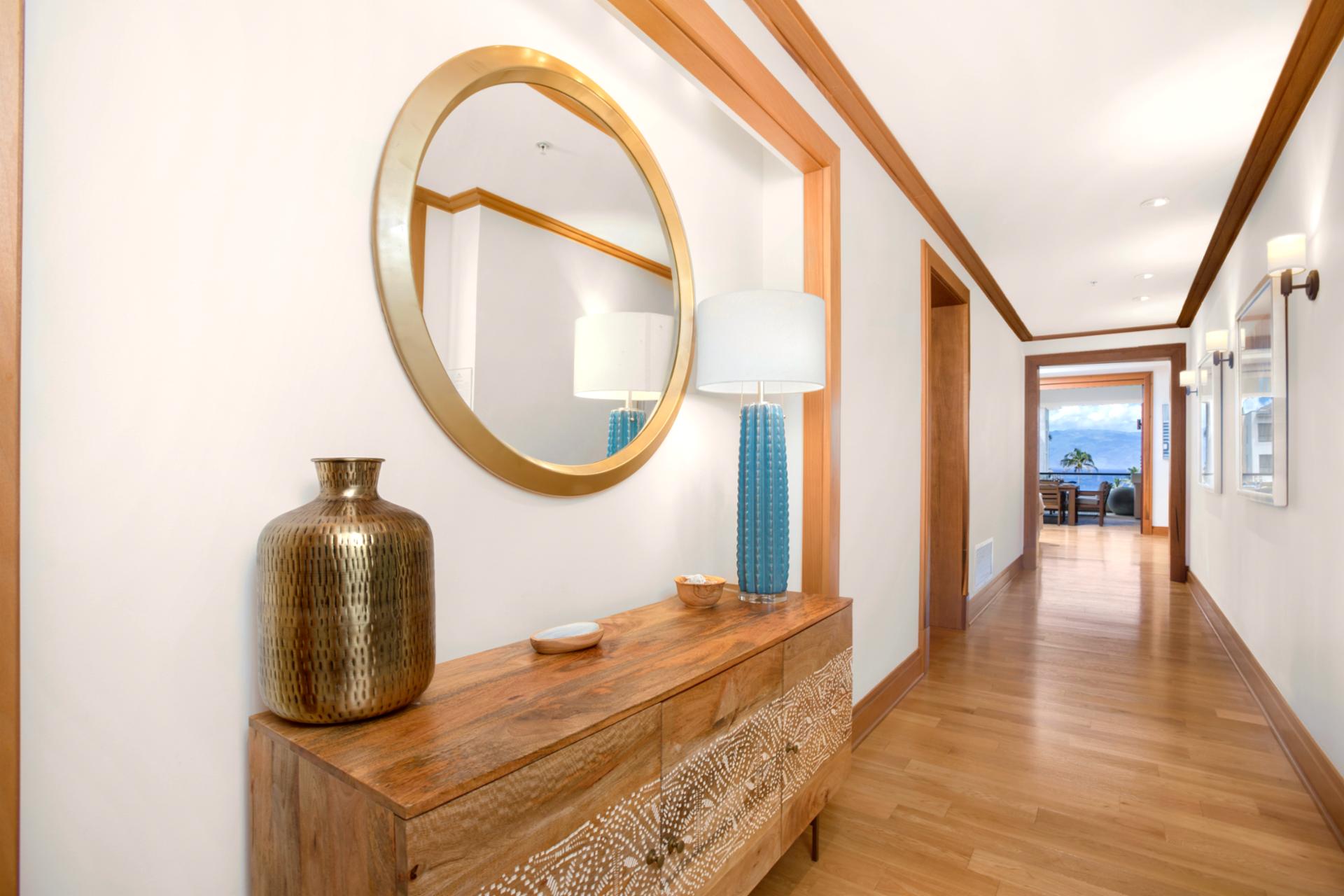 An artful hallway framed by warm woods, designer lighting, and coastal glimpses—where luxury greets you at the door   