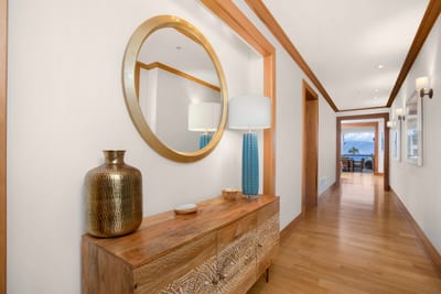 An artful hallway framed by warm woods, designer lighting, and coastal glimpses—where luxury greets you at the door MON-6301
