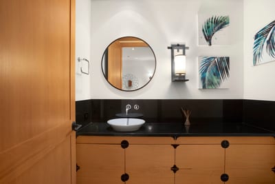 Step into this serene powder room where natural wood, coastal touches, and soft lighting create a calming retreat