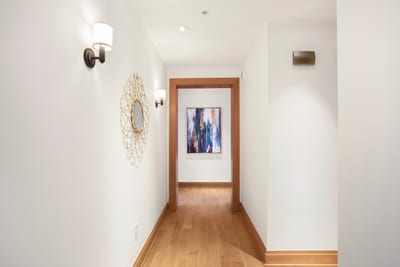 This softly lit corridor leads you into comfort, blending modern art, warm wood, and golden accents with grace MON-6301